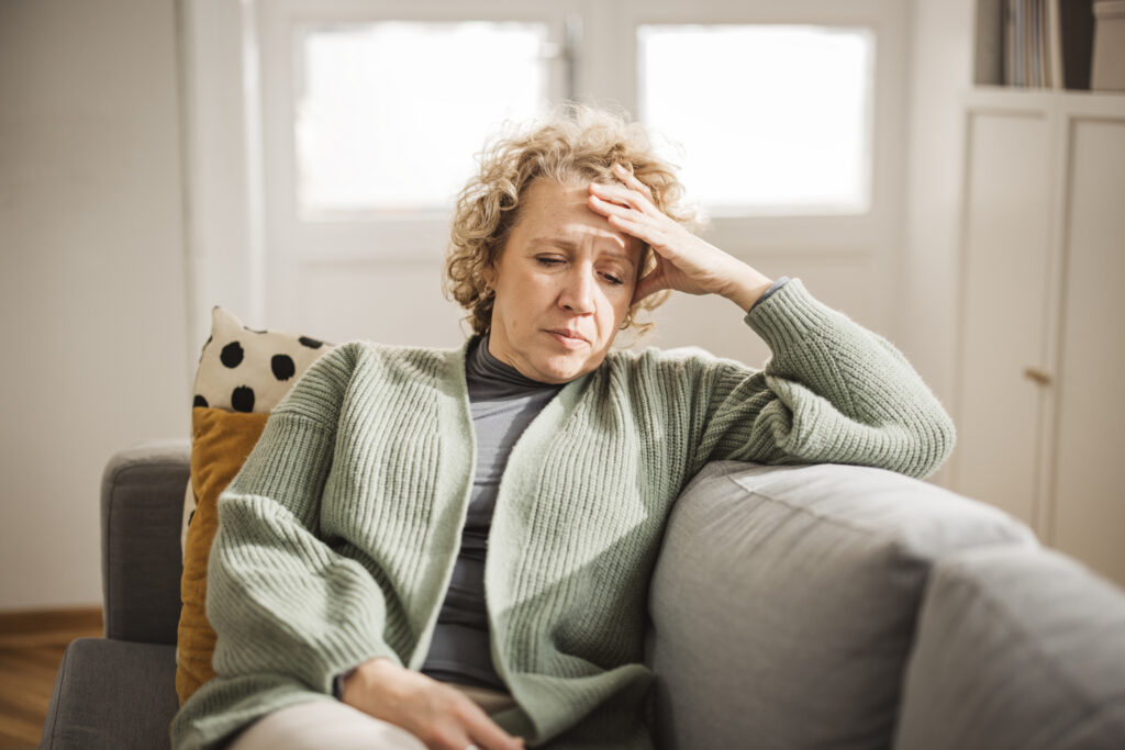 Older woman on sofa with head in hands