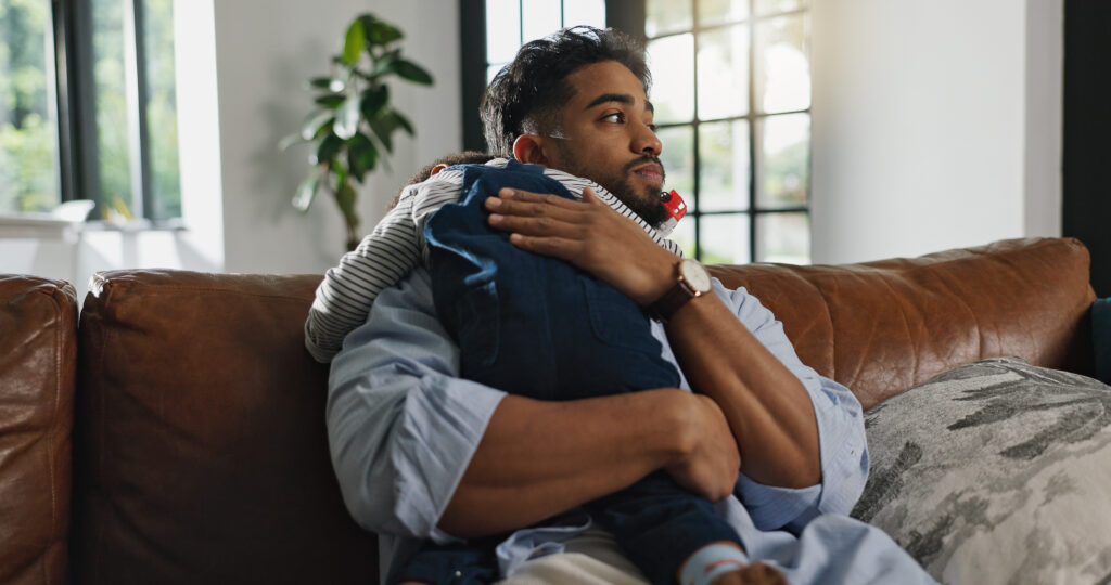 Young man with baby on sofa