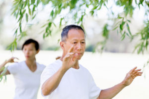 Older couple practicing tai-chi in the park to help with osteoporosis. 